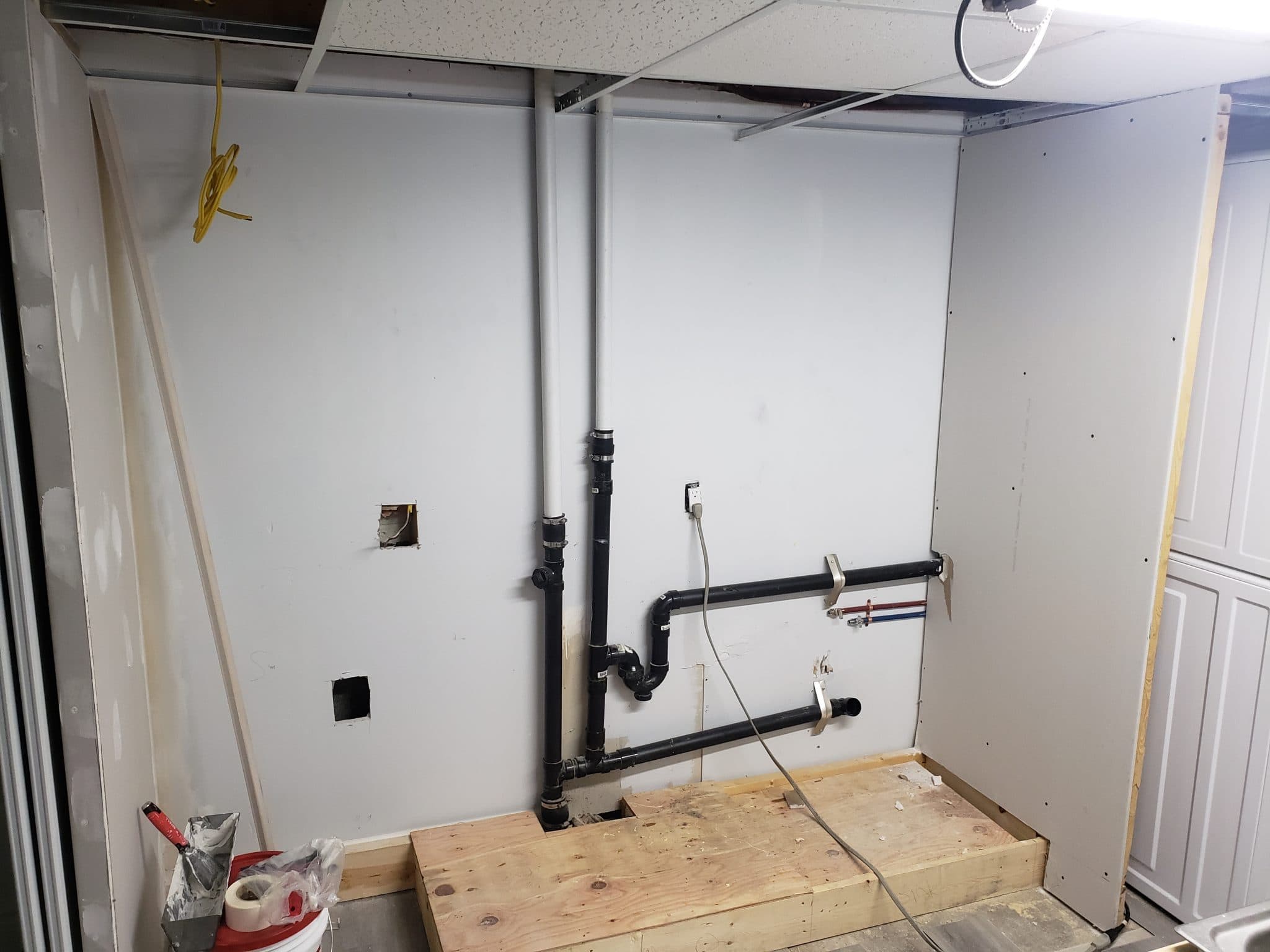 Bare basement wall with rough-in plumbing before the kitchenette build